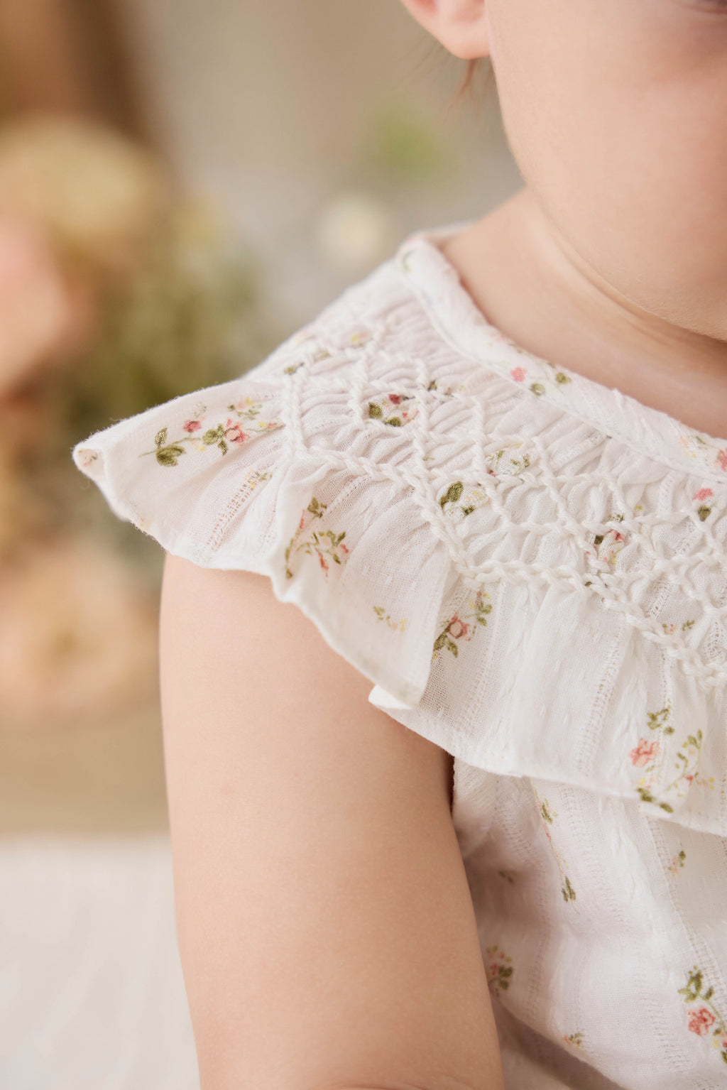Haut en coton biologique blanc à imprimé floral vintage avec encolure à volants et manches courtes.